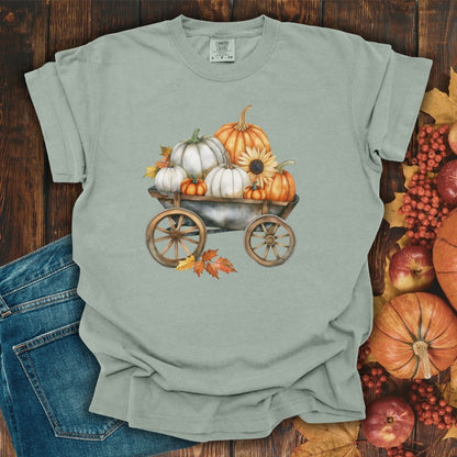 Bay green garment-dyed cotton t-shirt with a watercolor rustic wagon full of white and orange pumpkins and sunflowers.