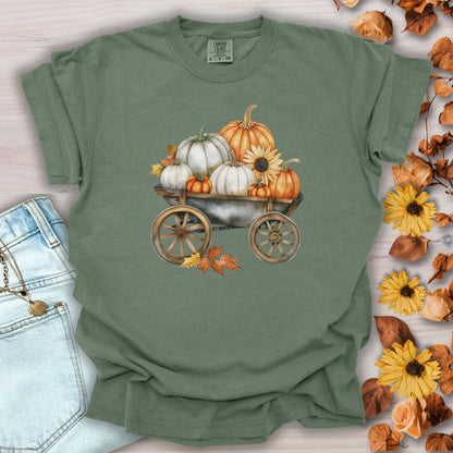 Moss green t-shirt with a watercolor rustic wagon piled with white and orange pumpkins, sunflowers, and leaves.