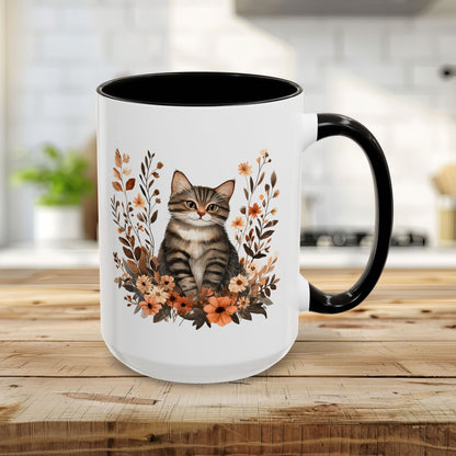 15oz white ceramic mug with a black handle and interior, featuring a tabby cat surrounded by autumn wildflowers.