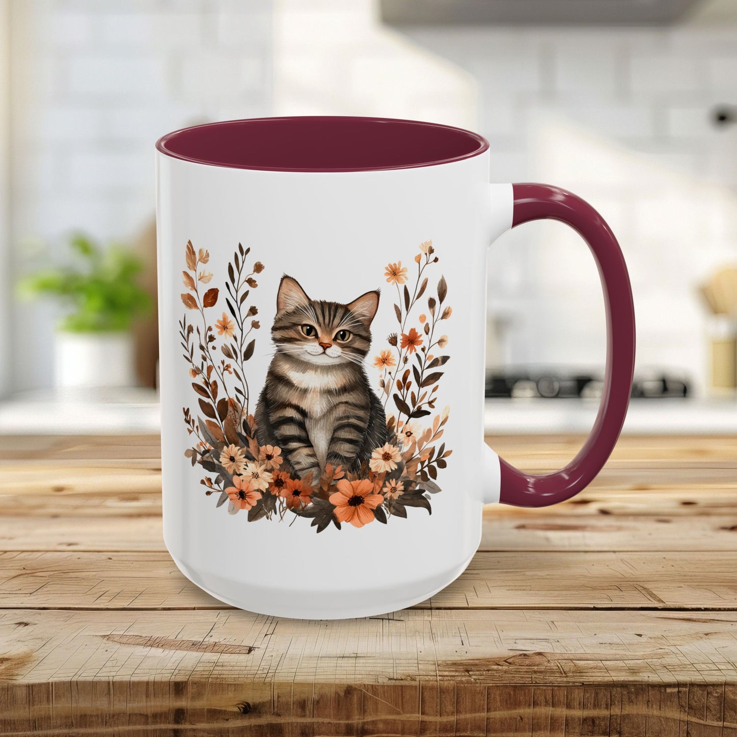 15oz white ceramic mug with a tabby cat and autumnal wildflowers, maroon interior and handle.