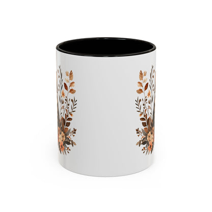 White ceramic mug with black interior and handle, featuring autumnal floral designs on the sides.
