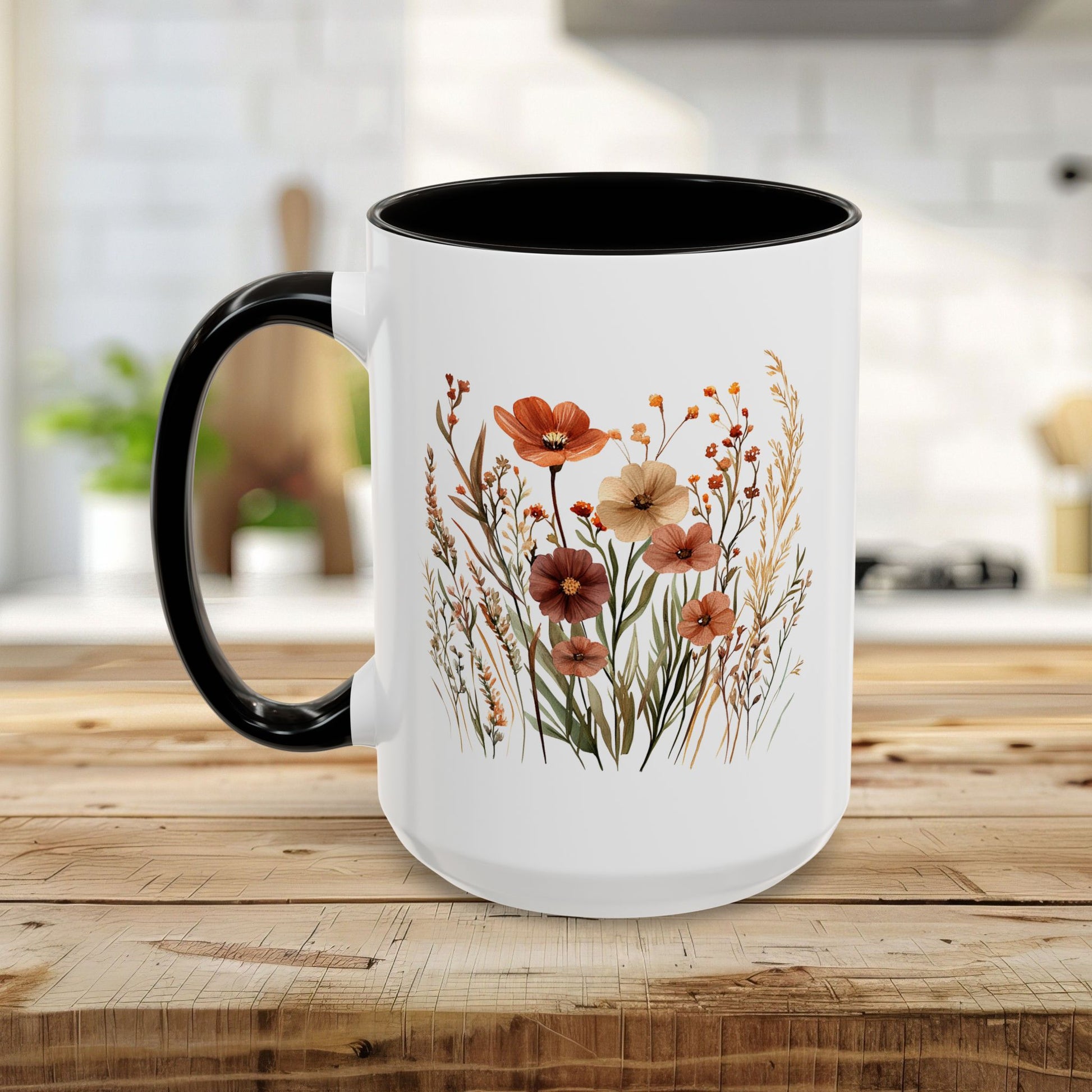 White ceramic mug with black handle and interior, featuring painterly autumn wildflowers in warm golds, rusts, and deep greens.
