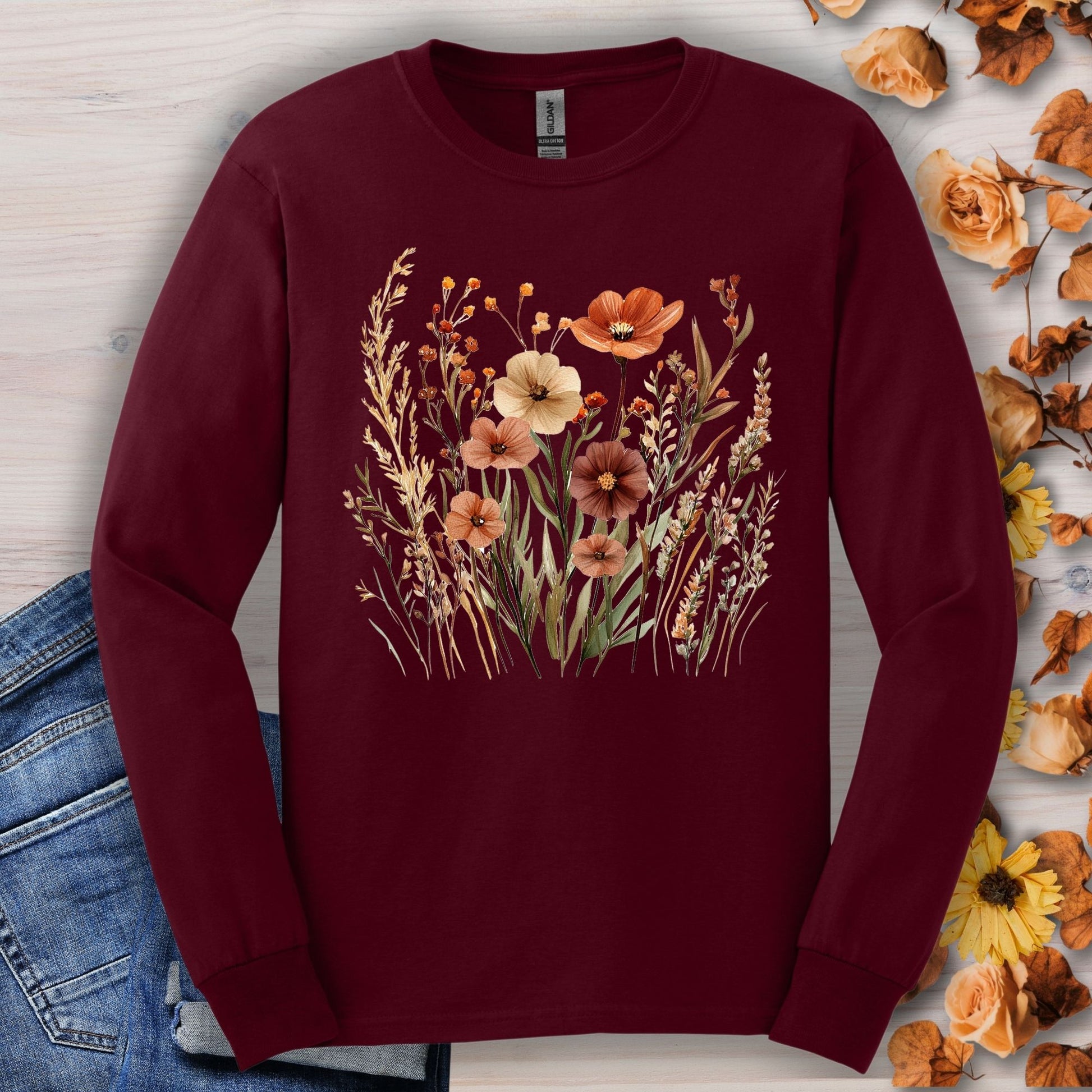 Maroon long-sleeve tee with watercolor autumn wildflowers, shown with jeans and fall leaves.