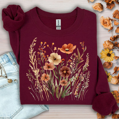 Maroon cotton-blend sweatshirt with watercolor autumn wildflowers and poppies design, next to jeans.