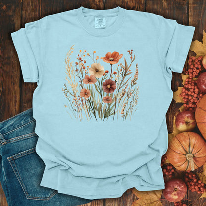 Chambray cotton t-shirt with autumn wildflowers in rust, ochre, plum, and sage, on a wooden background.