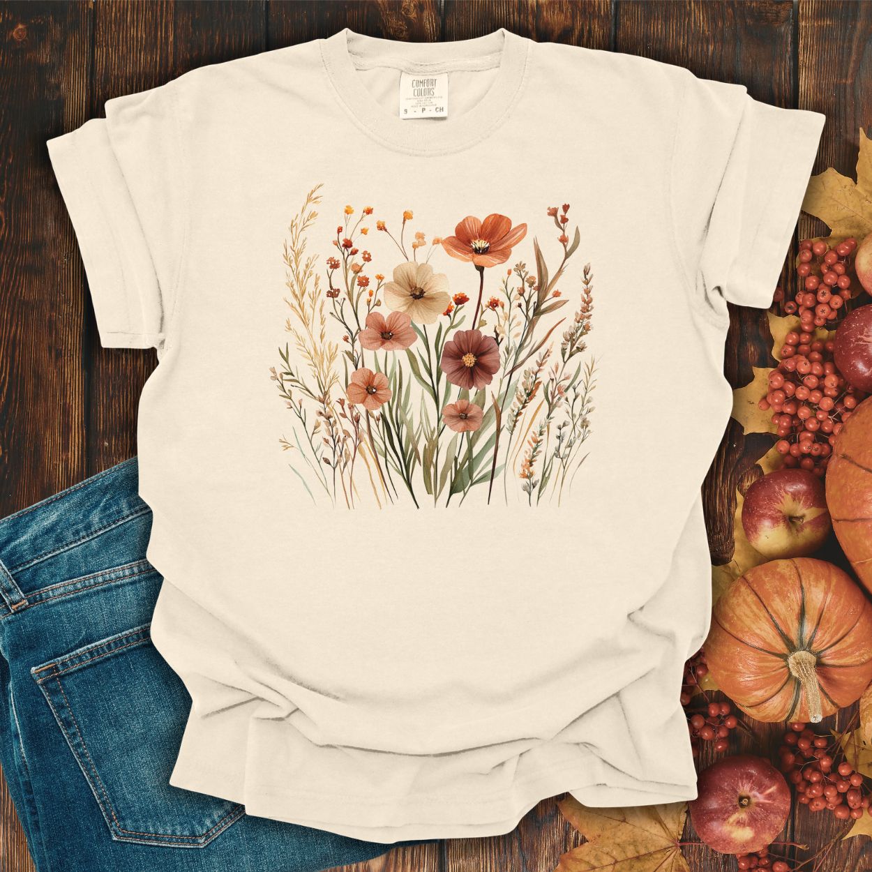 Ivory relaxed-fit cotton t-shirt with watercolor autumn wildflowers in rust, ochre, plum, and sage.