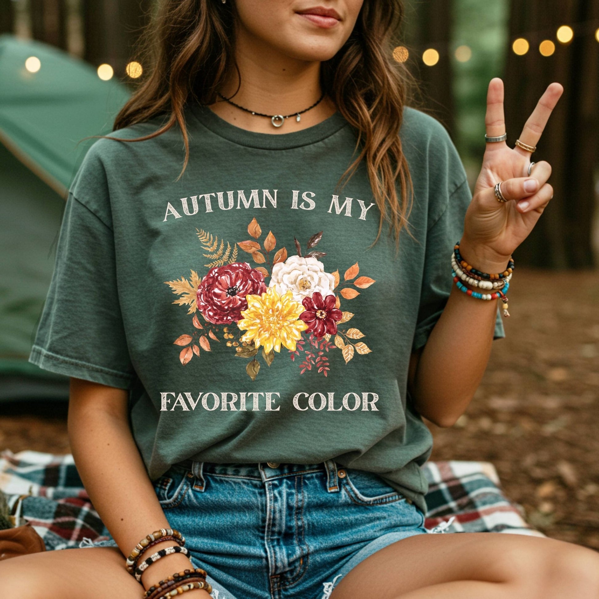 Woman in a dark green "Autumn Is My Favorite Color" t-shirt with watercolor fall flowers.