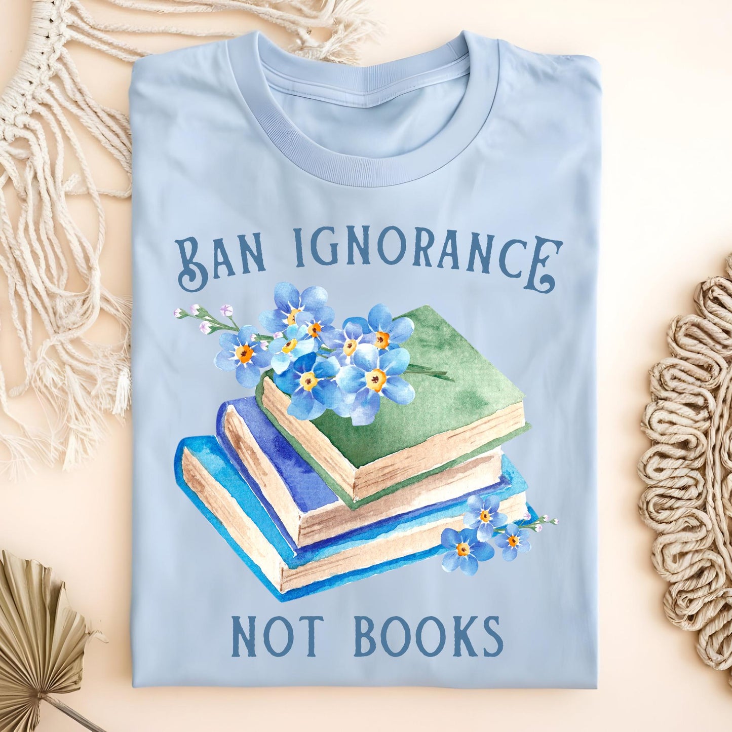 Light blue S cotton t-shirt with "Ban Ignorance, Not Books" text and watercolor vintage books with forget-me-nots.