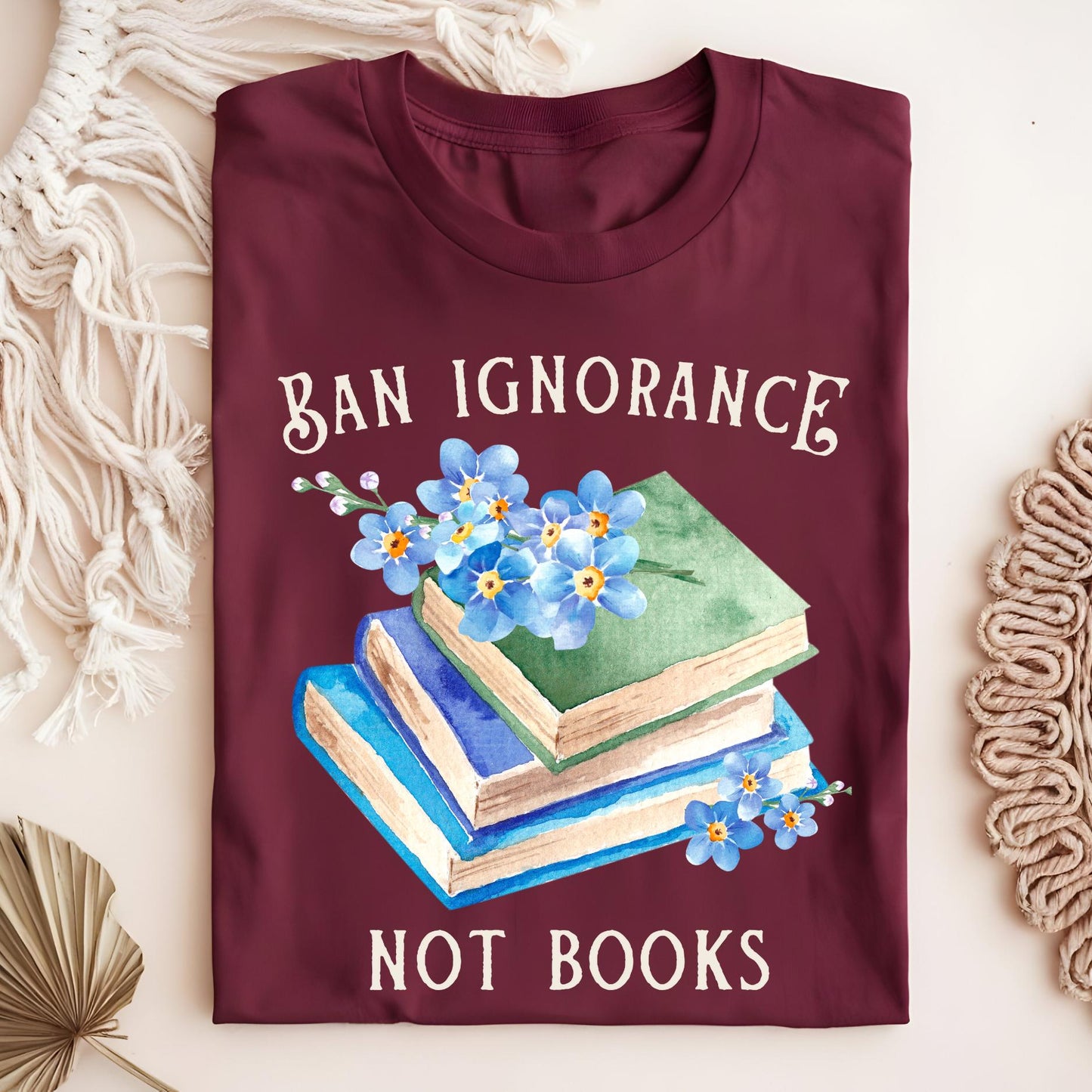 Maroon S t-shirt with "Ban Ignorance, Not Books" text and watercolor vintage books with blue forget-me-nots.