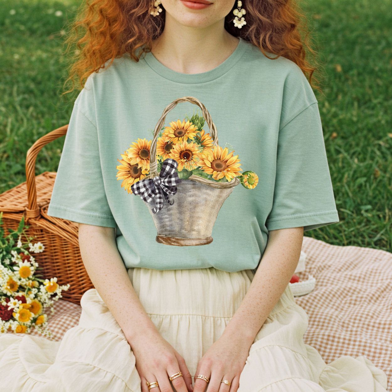 Garment-dyed sage green t-shirt with a watercolor basket of sunflowers and a gingham bow.