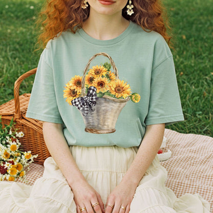 Garment-dyed sage green t-shirt with a watercolor basket of sunflowers and a gingham bow.