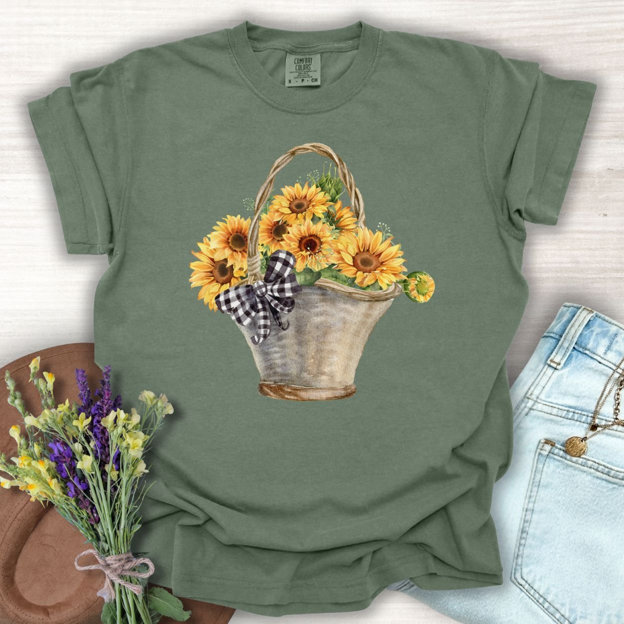 Moss green garment-dyed t-shirt with a hand-painted watercolor basket of sunflowers and a gingham bow.