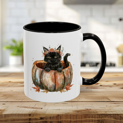 White ceramic 11oz mug with black interior/handle, featuring a watercolor black kitten in a pumpkin with fall leaves.