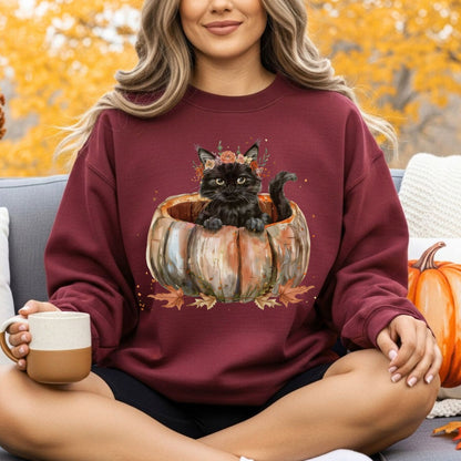 Woman in a maroon sweatshirt with a watercolor black cat in a pumpkin and autumn flowers.