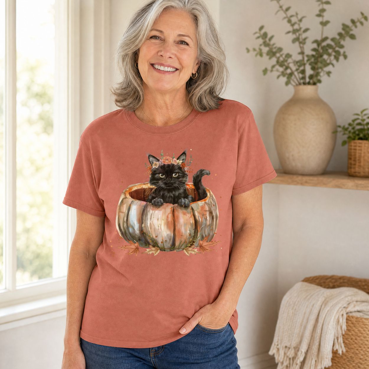 Woman in a relaxed-fit, rust-colored Comfort Colors t-shirt with a watercolor black cat in a pumpkin design.