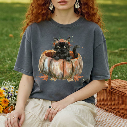 Comfort Colors t-shirt with a watercolor black cat in a pumpkin surrounded by autumn flowers.