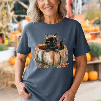 Woman in a navy Comfort Colors t-shirt with a watercolor black cat in a pumpkin and autumn flowers.