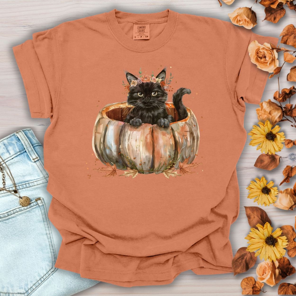 Yam Comfort Colors t-shirt with a watercolor black cat in a pumpkin surrounded by autumn flowers.