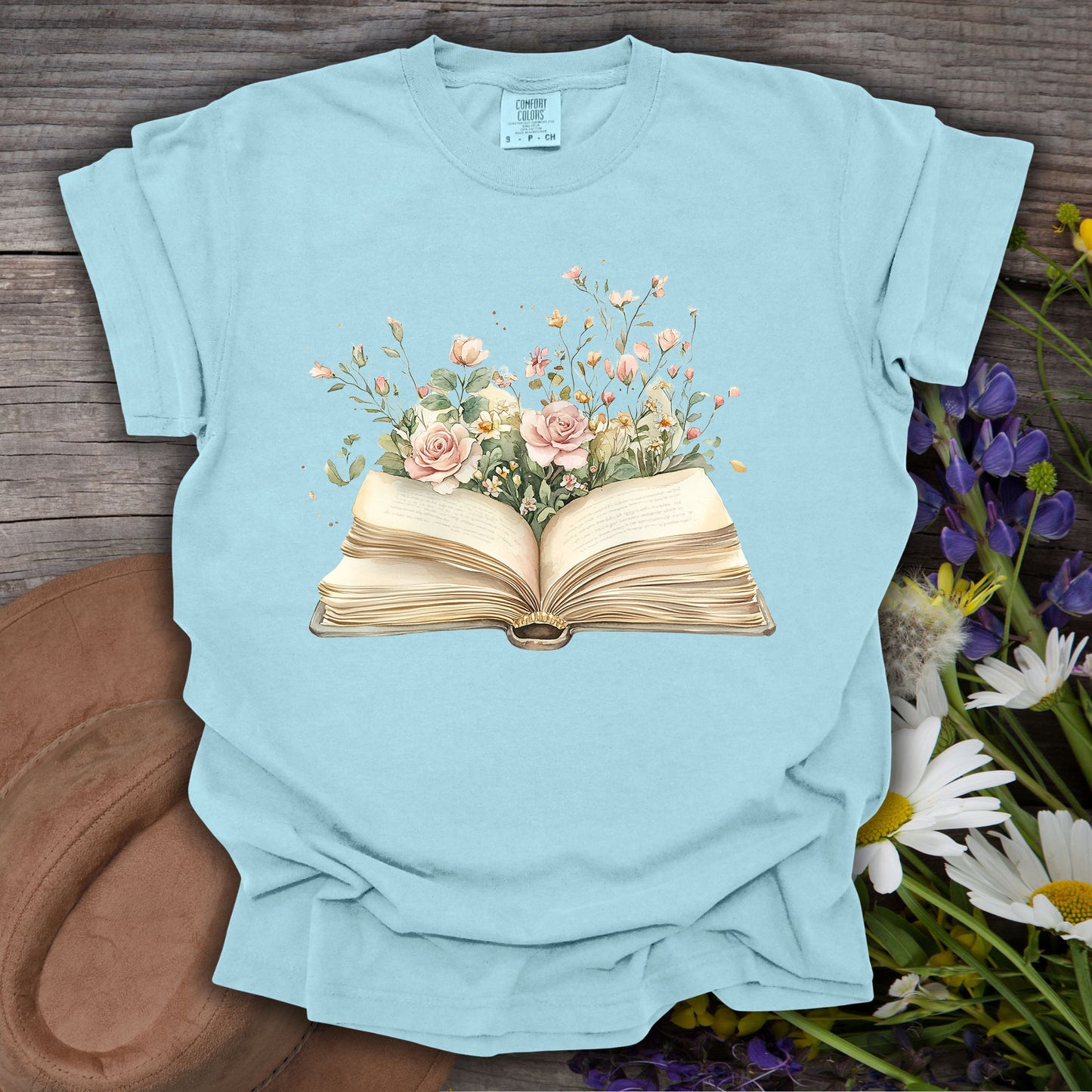 Chambray S t-shirt with a watercolor illustration of an open book blooming with pink roses and wildflowers.