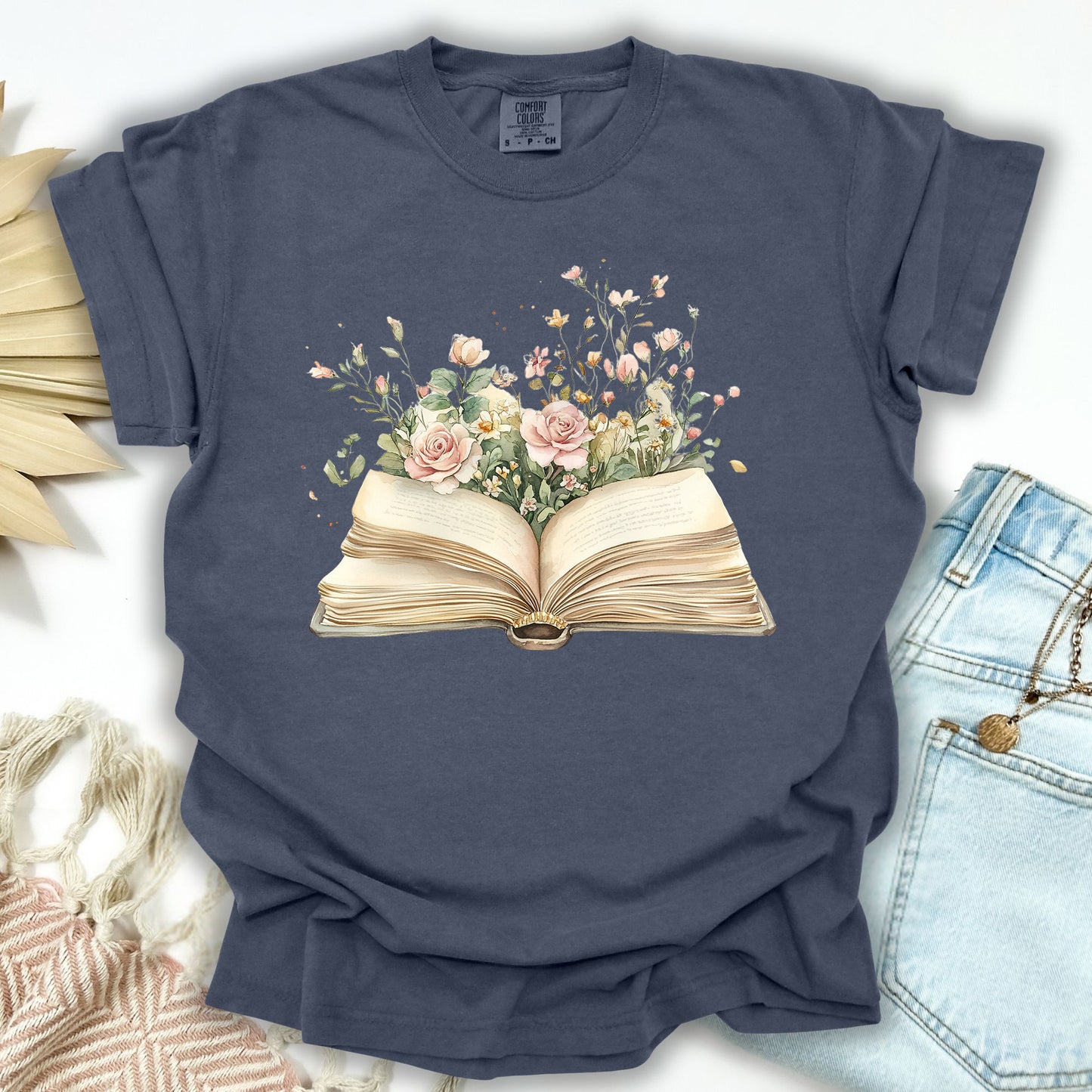 Denim S t-shirt with a watercolor illustration of an open book overflowing with pink roses and wildflowers.