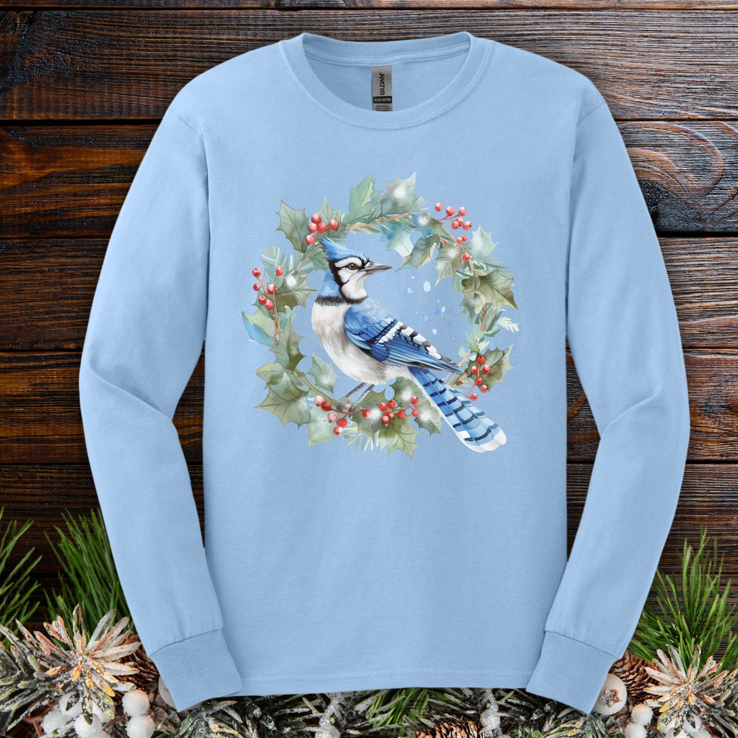Light blue long sleeve tee with a watercolor blue jay in a holly wreath design.