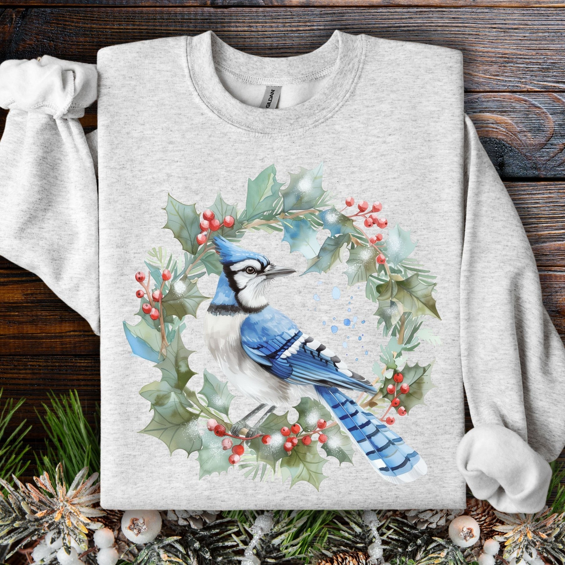 Light gray Gildan 18000 sweatshirt with a watercolor blue jay in a holly berry wreath design.