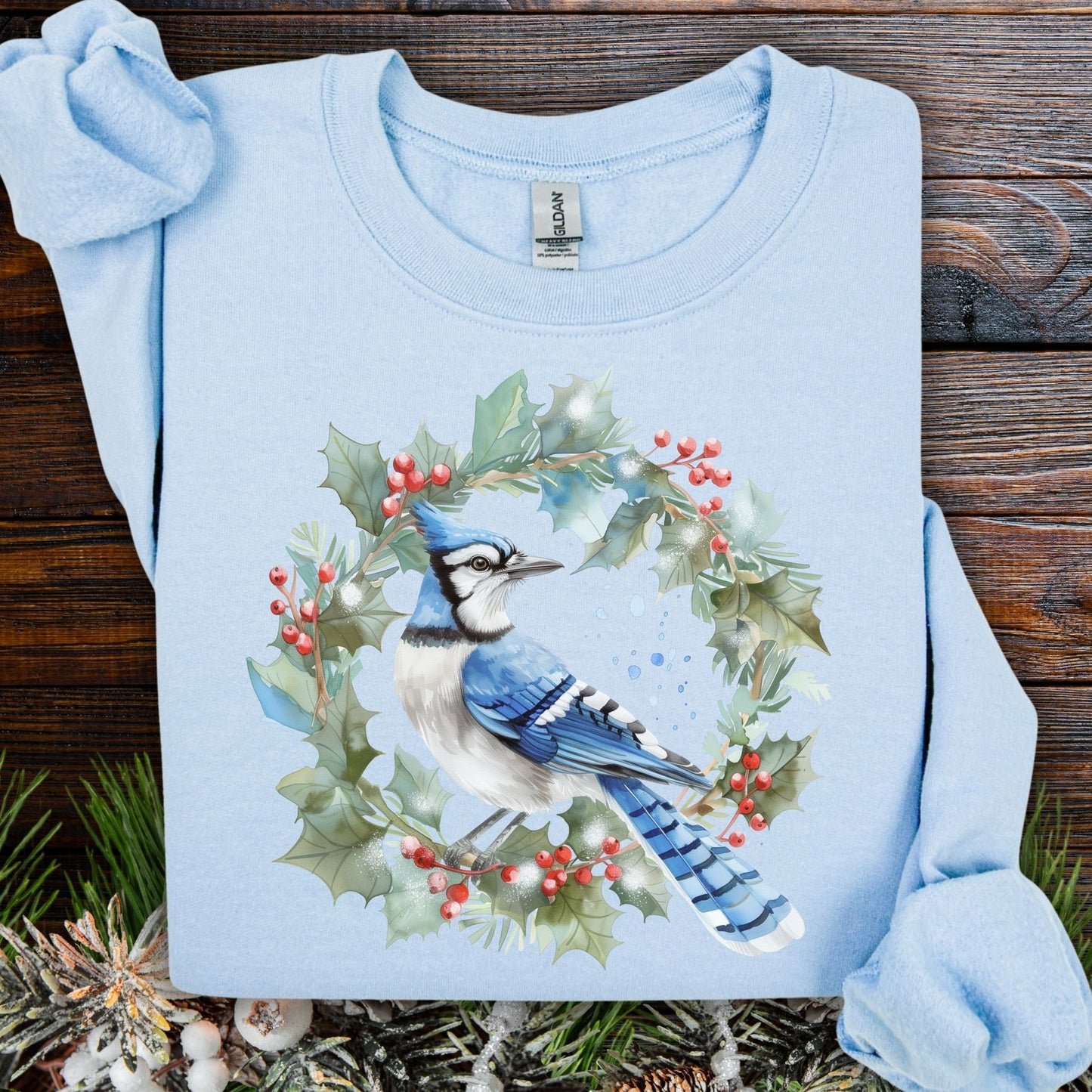 Light blue Gildan 18000 sweatshirt with a watercolor blue jay in a holly wreath design.