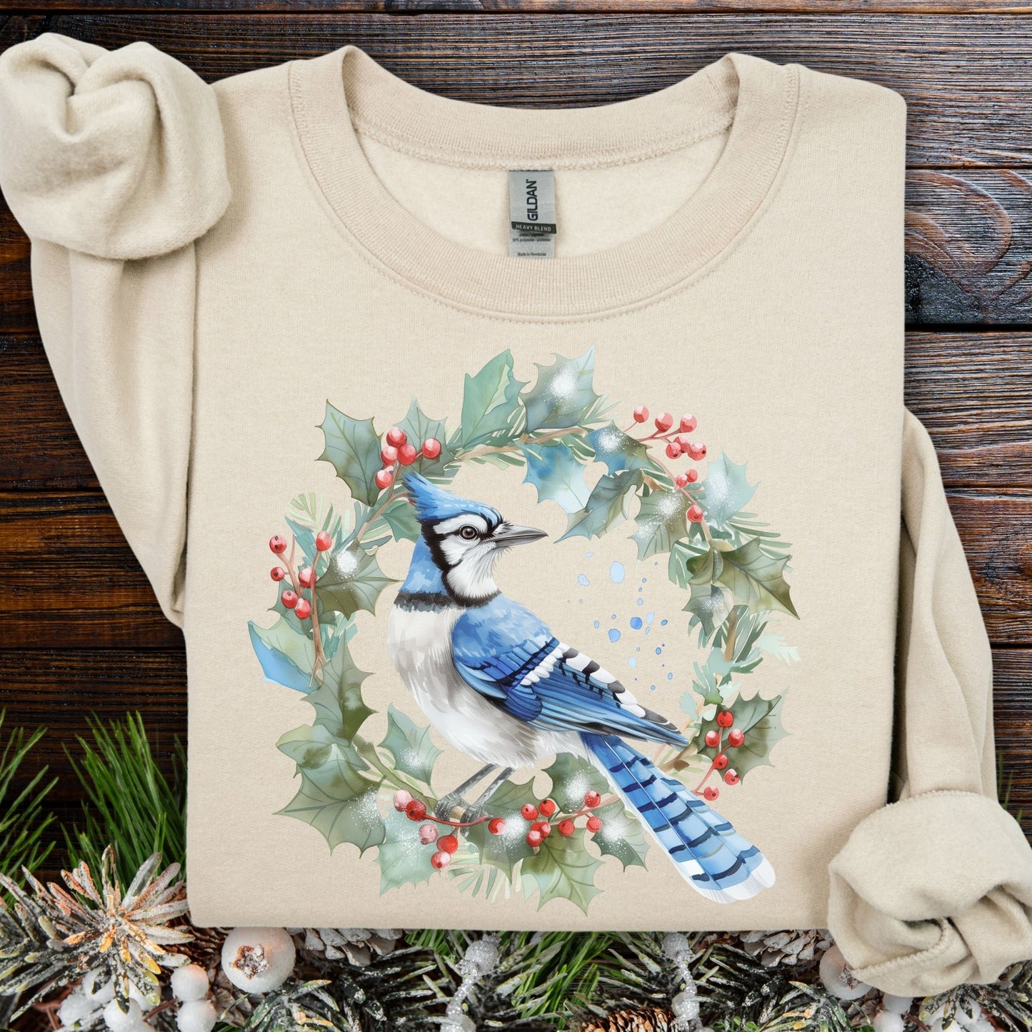 Sand Gildan 18000 sweatshirt with a watercolor blue jay in a holly wreath design.