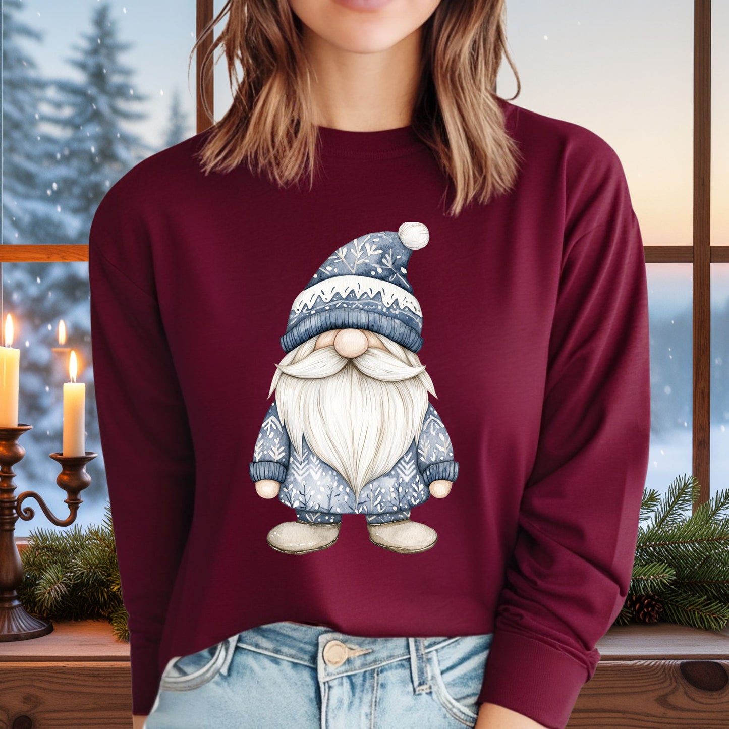 Maroon long sleeve tee with a hand-illustrated blue Nordic gnome, worn by a person in front of a winter window.