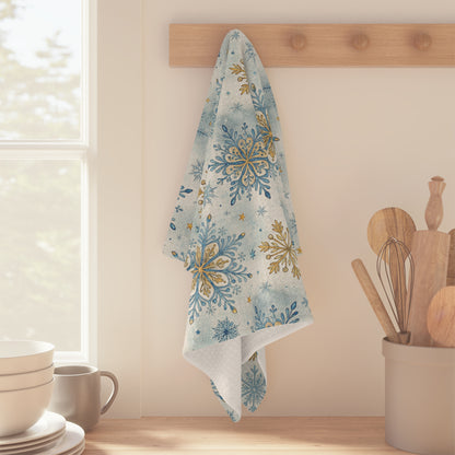 Blue and gold snowflake pattern microfiber tea towel hanging on a wooden peg in a kitchen.