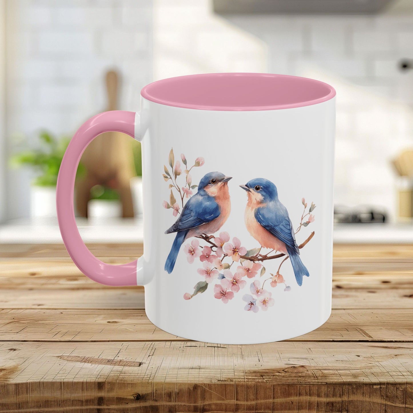 White ceramic mug with pink handle and interior, featuring watercolor bluebirds on cherry blossoms.