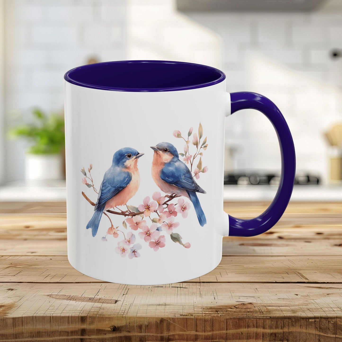 11oz glossy ceramic mug with watercolor bluebirds on cherry blossoms, blue interior, and C-shaped handle.
