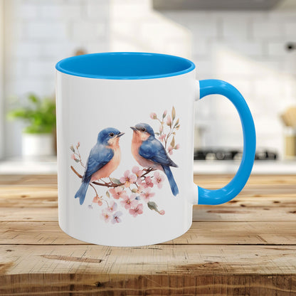 11oz glossy ceramic mug with watercolor bluebirds on cherry blossoms, light blue interior and handle.