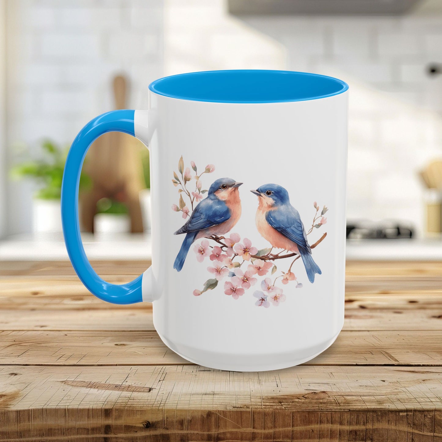 White ceramic mug with blue interior and handle, featuring watercolor bluebirds on cherry blossoms.