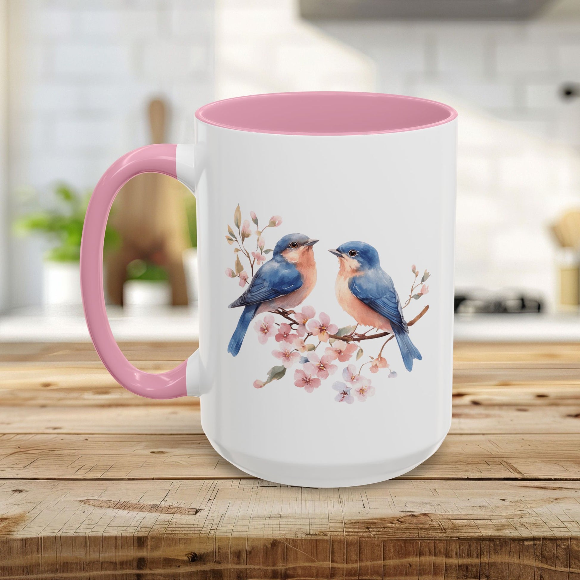 White ceramic mug with pink interior and handle, featuring watercolor bluebirds on cherry blossoms.