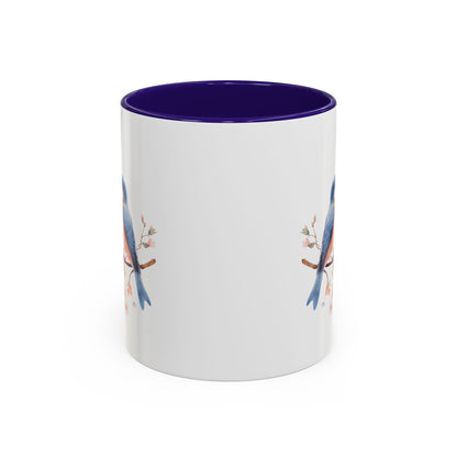White ceramic mug with bluebirds on cherry blossoms, purple interior, and C-shaped handle.