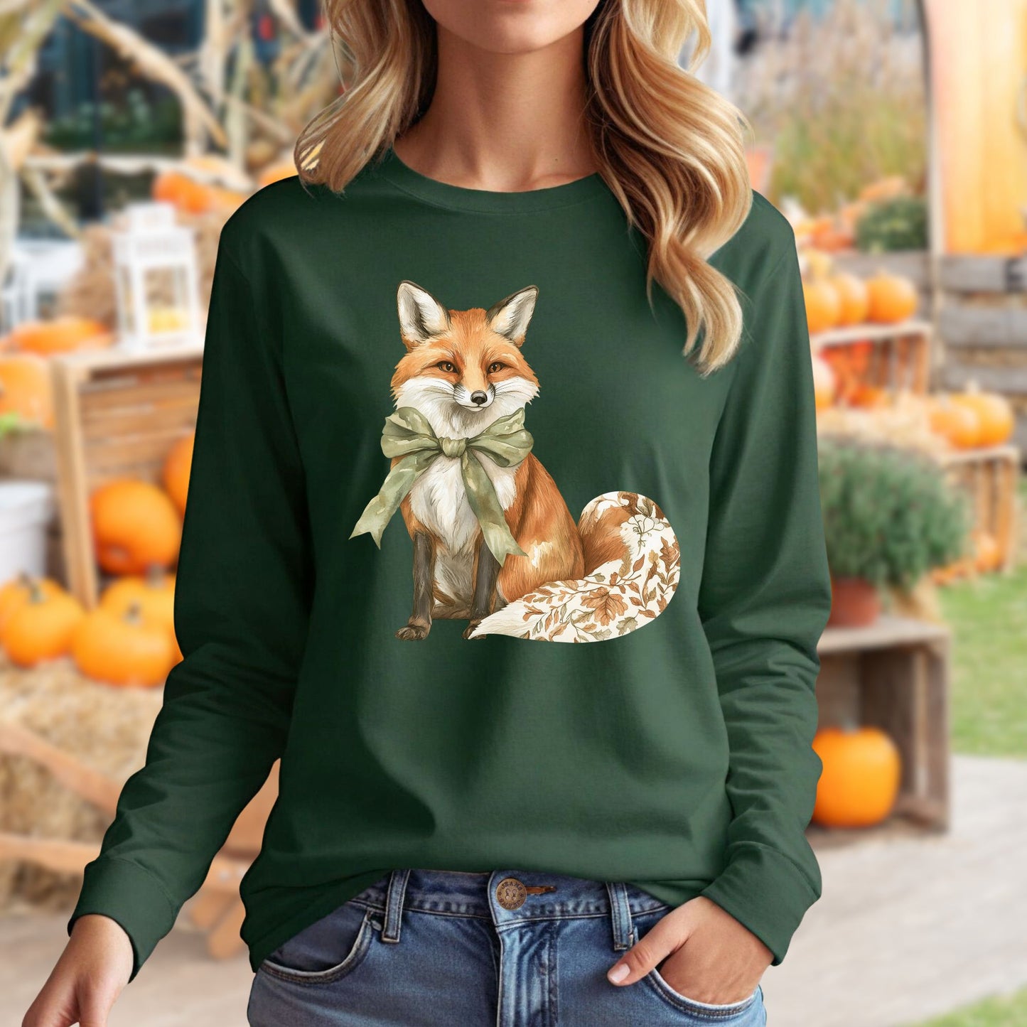 Woman in a dark green long sleeve tee with a watercolor fox, green bow, and autumn botanicals on its tail.