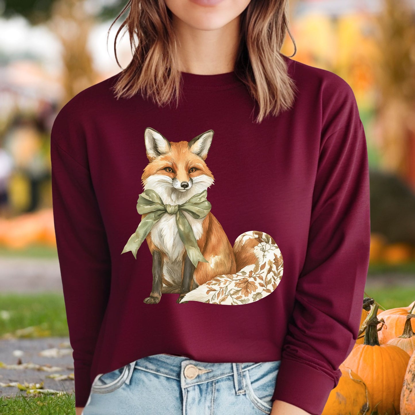 Maroon long sleeve tee with a watercolor fox, green bow, and autumn botanicals on its tail.