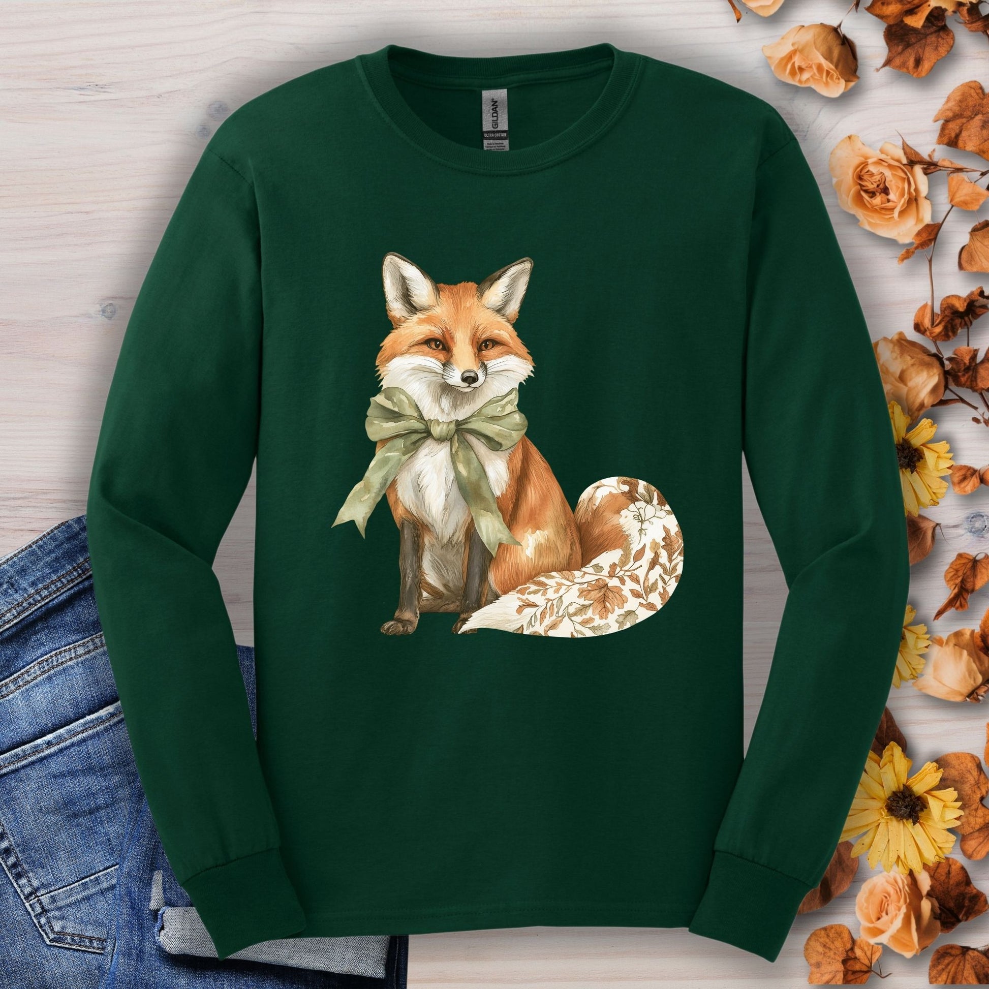 Forest Green Gildan long sleeve tee with a watercolor fox, green bow, and autumn botanicals on its tail.