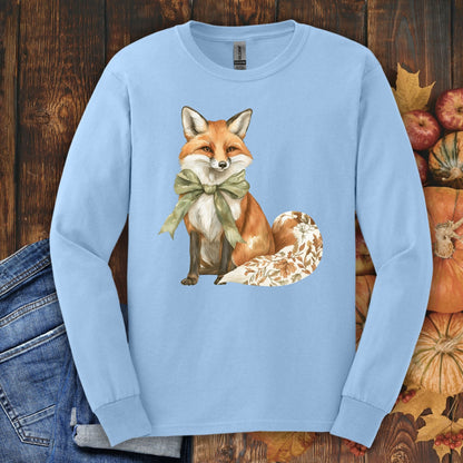 Light blue long sleeve tee with a watercolor fox, green bow, and autumn botanicals on its tail.
