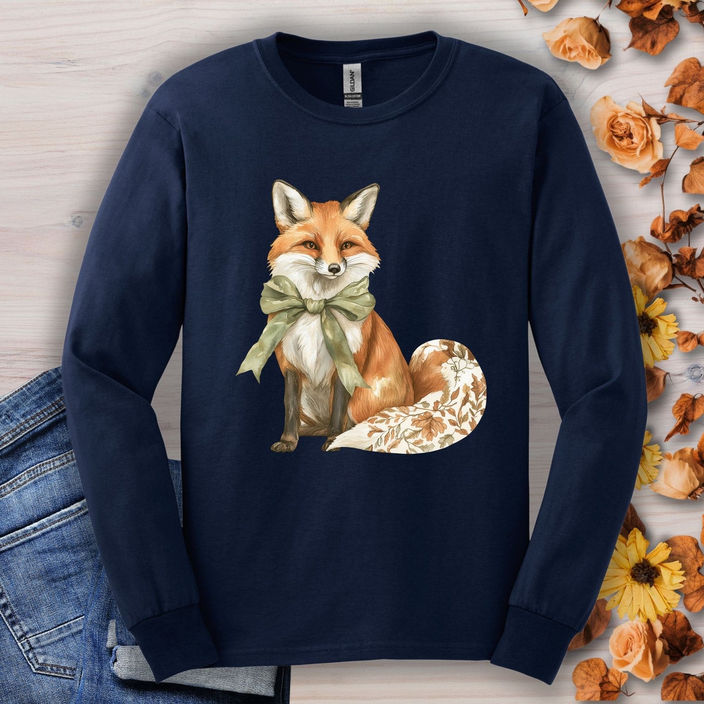Navy long sleeve tee with a watercolor fox, green bow, and autumn botanicals on its tail.