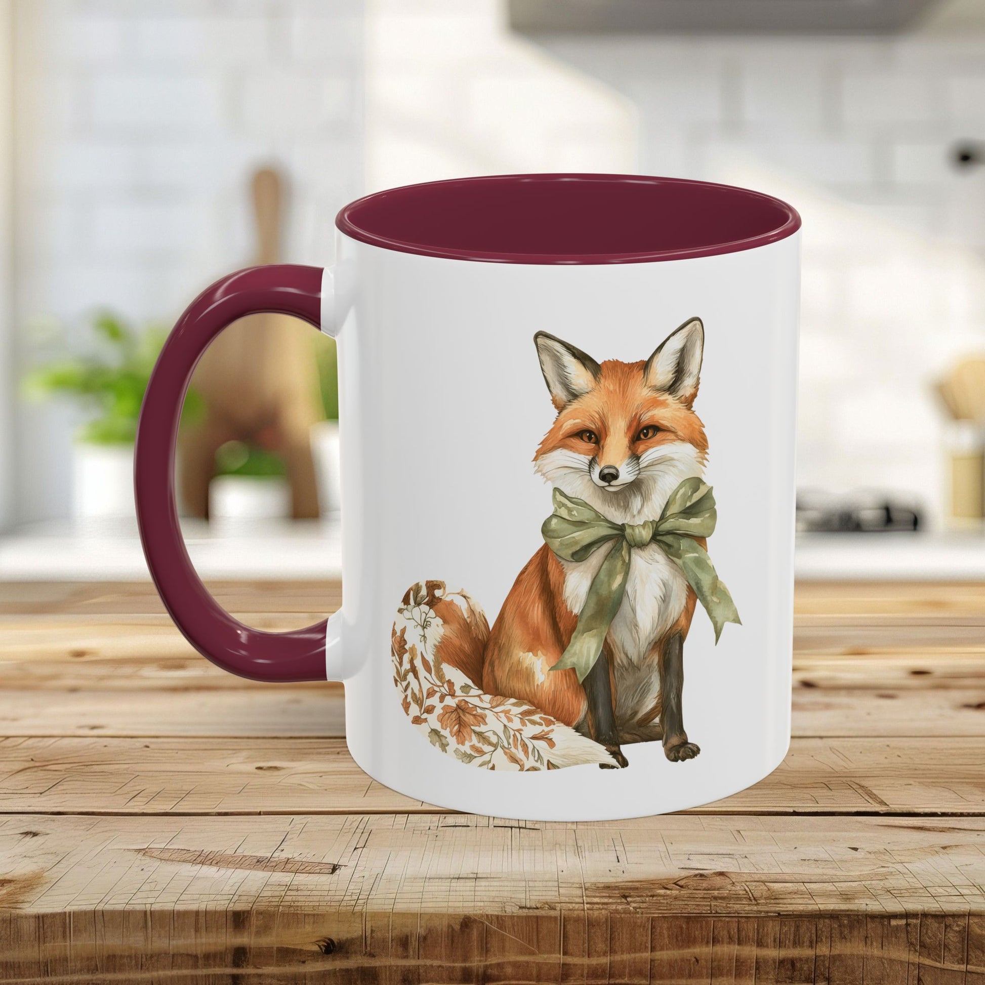 White ceramic mug with a watercolor autumn fox wearing a green bow, featuring a burgundy handle and interior.
