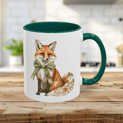 White ceramic 11oz mug with a green handle and interior, featuring a watercolor fox with a green bow and autumn leaf tail.