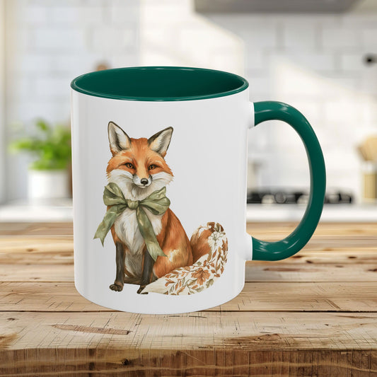White ceramic 11oz mug with a green handle and interior, featuring a watercolor fox with a green bow and autumn leaf tail.