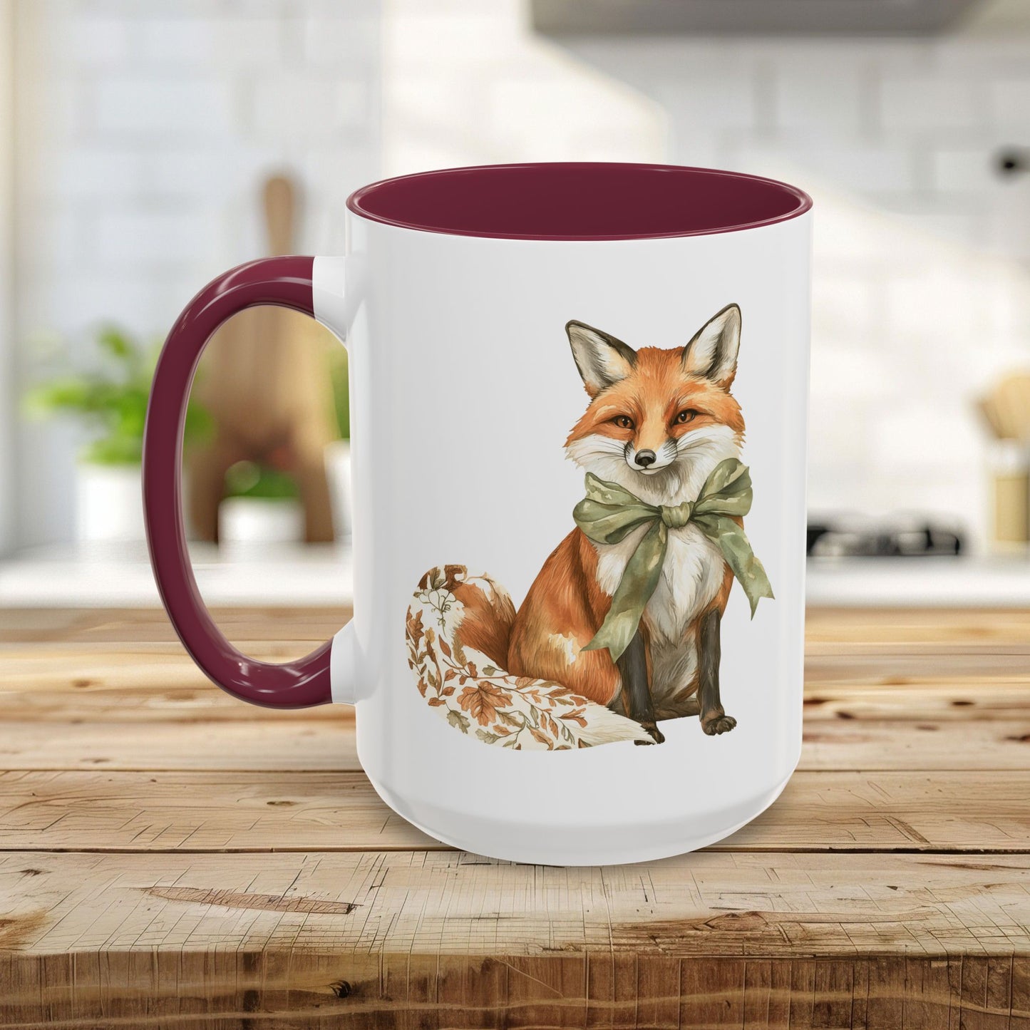 White ceramic mug with a watercolor fox wearing a green bow, featuring a maroon handle and interior.