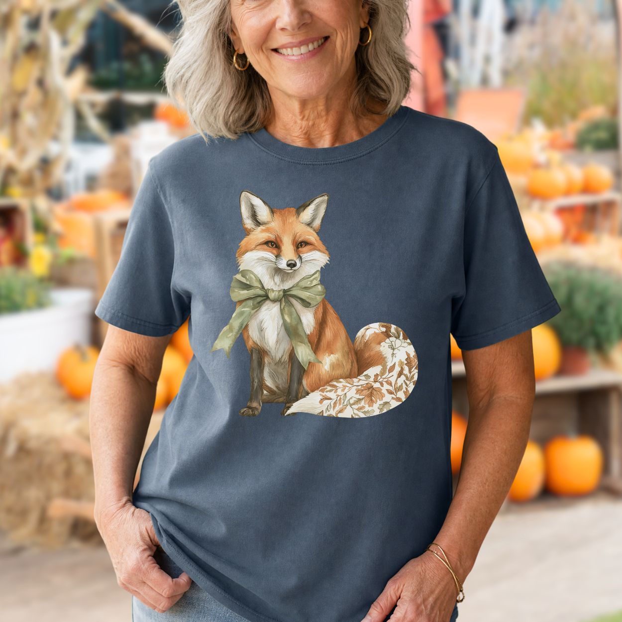 Garment-dyed navy cotton t-shirt with a watercolor fox wearing a sage-green bow and a leaf-patterned tail.