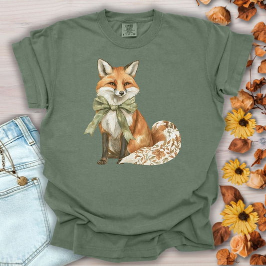 Moss green garment-dyed t-shirt with a watercolor fox wearing a sage green bow and a leaf-patterned tail.