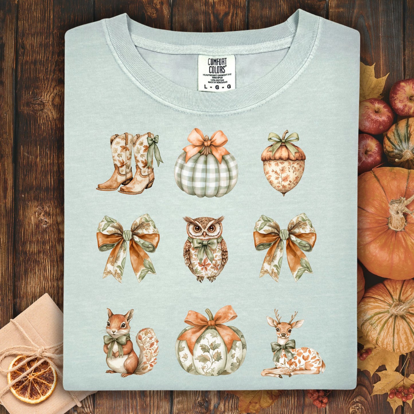 Light blue Comfort Colors t-shirt with boho fall art: boots, pumpkins, acorn, owl, squirrel, and bows.