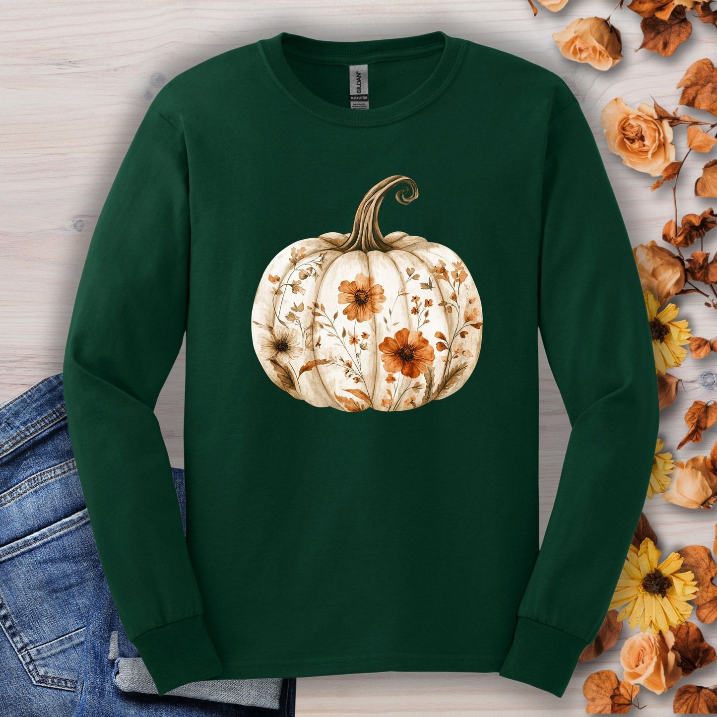 Forest Green long sleeve tee with a white boho floral pumpkin design, surrounded by autumn leaves.