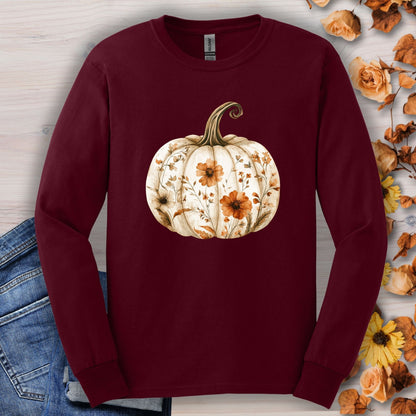 Maroon Gildan long sleeve tee with a white boho floral pumpkin design, surrounded by autumn leaves.